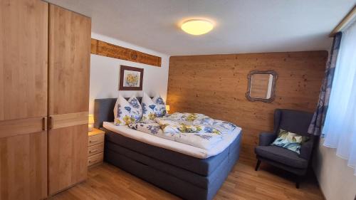 a bedroom with a bed and a chair in it at Chalet Lärchforst in Aich