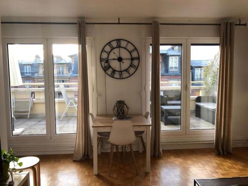 une pièce avec une table et une horloge au mur dans l'établissement Terrasse avec Vue, à Paris