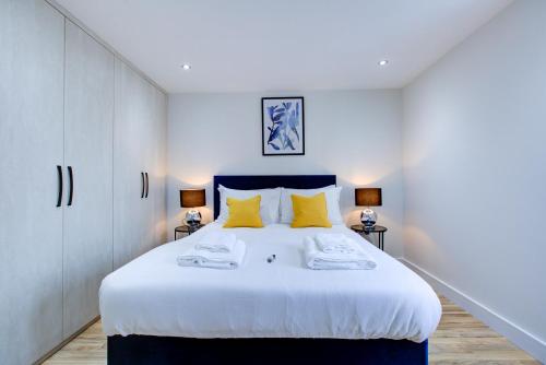 um quarto com uma grande cama branca com almofadas amarelas em Hybrid Resi - Uxbridge em Uxbridge