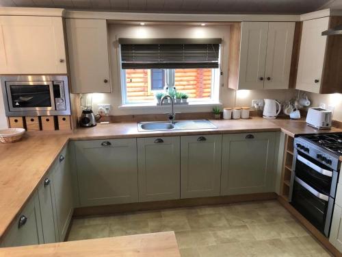 a kitchen with white cabinets and a sink and a window at Griffon Lodge in Morpeth