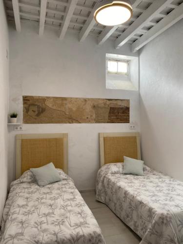 two beds in a room with white walls at Casa de Santa María in El Puerto de Santa María