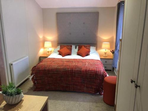 a bedroom with a large bed with red pillows at Griffon Lodge in Morpeth