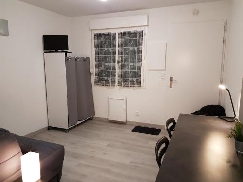 un salon avec une table et une fenêtre dans l'établissement Studio meublé équipé paisible, à Chambray-lès-Tours