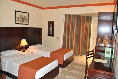 a hotel room with two beds and a window at Sharm Holiday Resort in Sharm El Sheikh