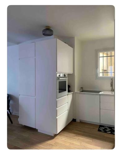 une cuisine avec des armoires blanches et un micro-ondes dans l'établissement Appartement cosy à Paris, à Paris