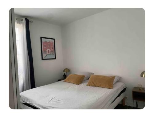 une chambre avec un lit blanc avec deux oreillers dans l'établissement Appartement cosy à Paris, à Paris