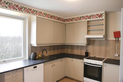 a kitchen with white cabinets and a window at Eiðar - Apartments in Eiðar