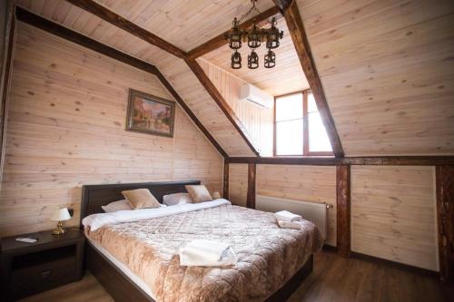 ein Schlafzimmer mit einem großen Bett in einem Zimmer mit Holzwänden in der Unterkunft Готель Бережани in Brzezhany