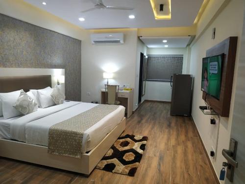 a bedroom with a bed and a flat screen tv at Le Tokyo Hotel Vithalapur in Vithalpur
