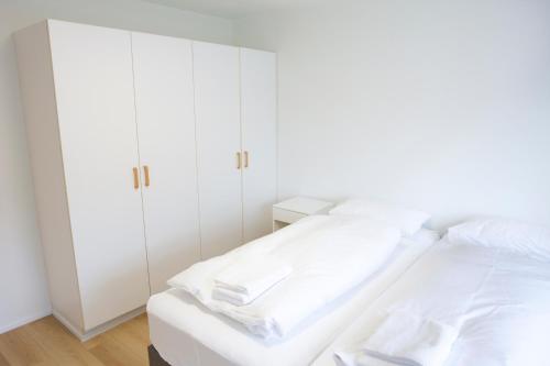 a white bedroom with white cabinets and a bed at Eiðar - Apartments in Eiðar