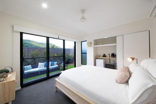 a bedroom with a white bed and a large window at Whitsunday Whisper Terrace - Townhouse Pets Airlie in Airlie Beach