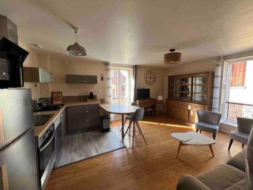 une cuisine et un salon avec une table et des chaises dans l'établissement APPARTEMENT CENTRE MEDIEVAL SPACIEUX AVEC ASCENSEUR, La suite cosy de la boëtie, à Sarlat-la-Canéda