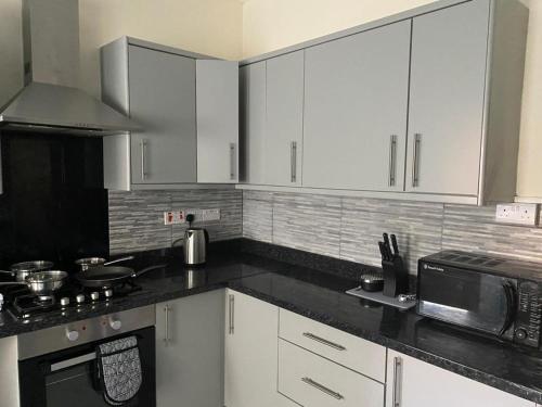 a kitchen with white cabinets and a black counter top at Chepstow House (5 BR with FREE on-steet parking) in Newport