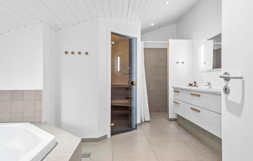 uma casa de banho branca com uma banheira e um lavatório em Beautiful Home In Blvand With Sauna em Blåvand