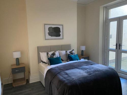 a bedroom with a large bed with blue pillows at Chepstow House (5 BR with FREE on-steet parking) in Newport