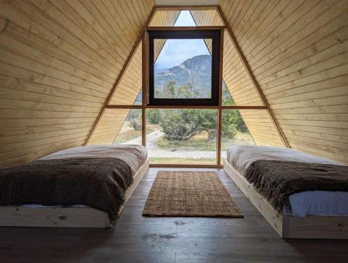 Duas camas num quarto com uma janela grande em Precioso refugio en Villa Castillo Servicio Outscape em Villa Cerro Castillo