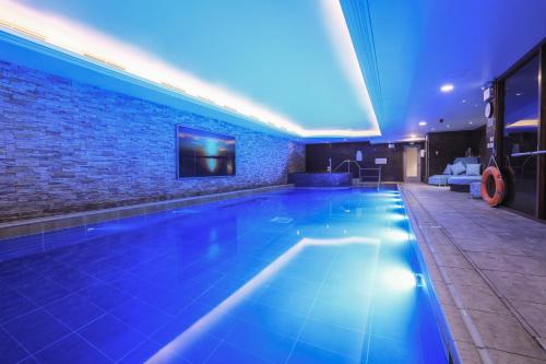 a swimming pool in a hotel with blue lighting at Harbour Hotel & Spa Christchurch in Christchurch