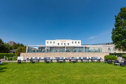 a group of chairs sitting on a lawn in front of a building at Harbour Hotel & Spa Christchurch in Christchurch