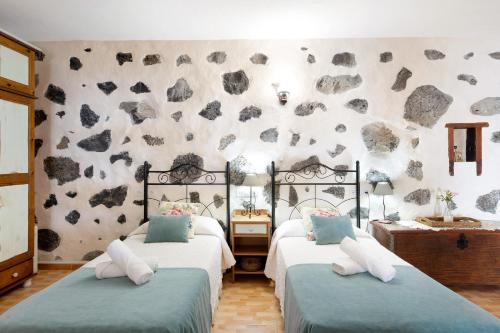 una camera con due letti e una parete di roccia di Casa Titi a Las Indias