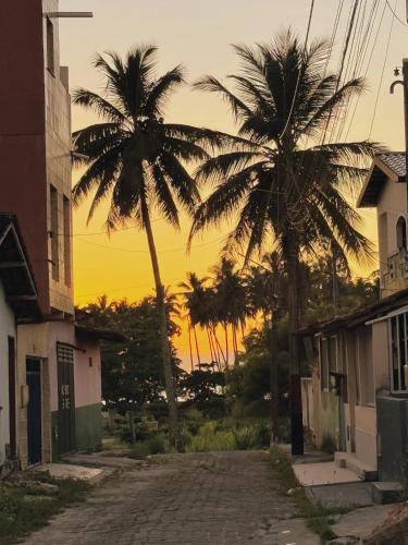 two palm trees on a street with the sunset in the background at Quarto aconchegante in Prado