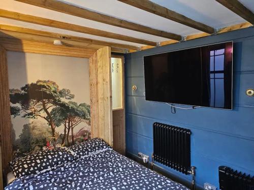 a bedroom with a blue wall with a flat screen tv at City Centre Stylish Hideaway in Exeter
