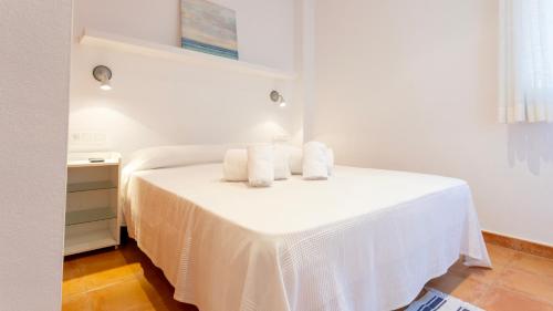 a bedroom with a white bed with towels on it at CANADELL BLOC B baixos 1ª in Calella de Palafrugell