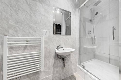 a white bathroom with a sink and a shower at Luxury Two Bedroom Flat right opposite to Harrods KB15 in London