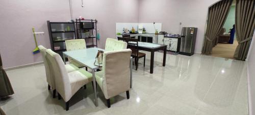 Un comedor con mesa y sillas y una cocina. en Homestay Azihan, en Pasir Puteh