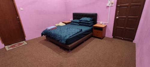 ein Schlafzimmer mit einem Bett in einem lila Zimmer in der Unterkunft Homestay Azihan in Pasir Puteh