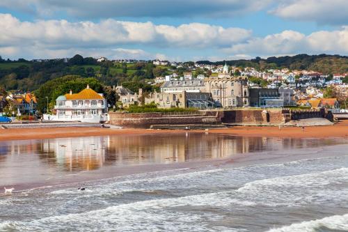 a view of a beach with buildings and the water at Beautiful Caravan With Decking At Hoburne Devon Bay, Ref 54058f in Paignton