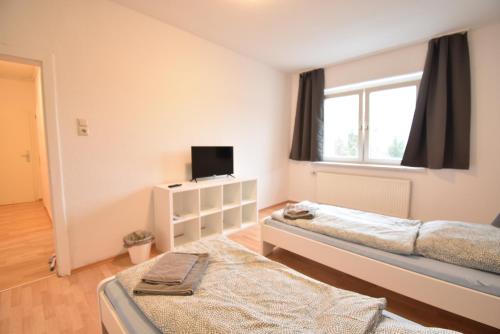 a bedroom with two beds and a tv and a window at CoreRooms - Apartment Bochum Wattenscheid in Bochum