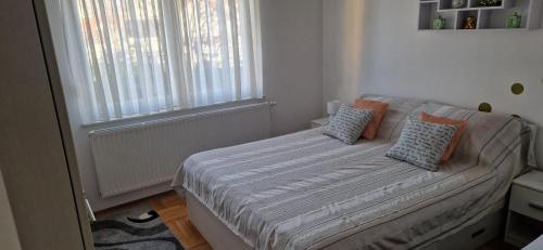 a small bedroom with a bed with pillows and a window at CENTRUM with private parking in Virovitica