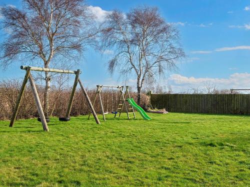 a playground with two swings in a field at 6 person holiday home in Sydals-By Traum in Østerby