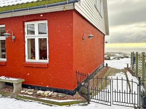 a red house with a white window and a bench at Holiday home Rønne VI in Rønne