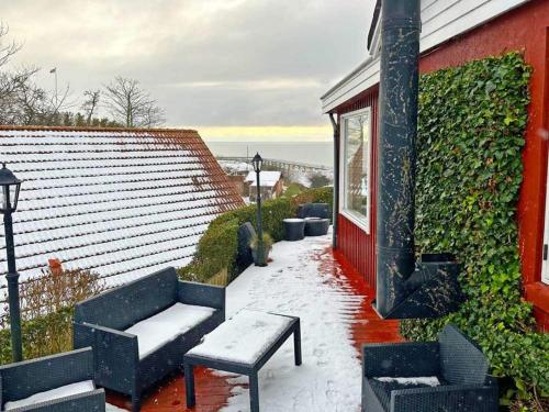 a snow covered patio with chairs and a bench and a building at Holiday home Rønne VI in Rønne