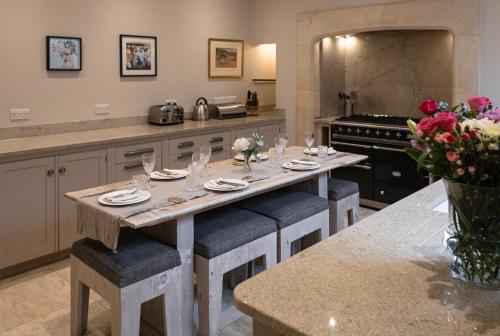 Cambridge House في باث: مطبخ مع طاولة مع كؤوس النبيذ والزهور