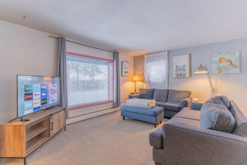 a living room with two couches and a flat screen tv at The Cozy Harriet Log Home in Fairbanks