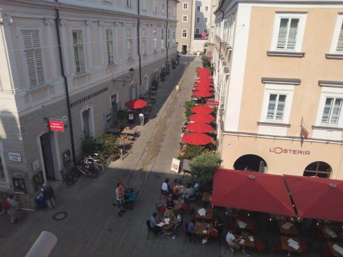 einen Blick über eine Straße mit Tischen und roten Sonnenschirmen in der Unterkunft arte vida boutique guesthouse in Salzburg