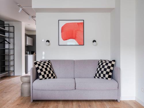 a living room with a couch and a painting at numa I Leo Apartments in Düsseldorf