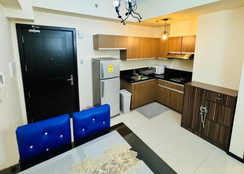 a kitchen with a table and blue chairs and a refrigerator at City Homes: The Radiance Manila Bay in Manila