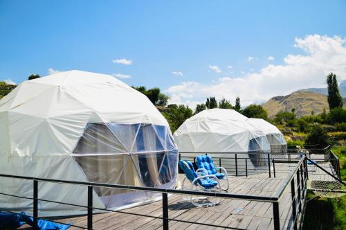 2 tiendas de campaña abovedadas en una terraza con sillas azules en SG Glamping Resort en Hunza