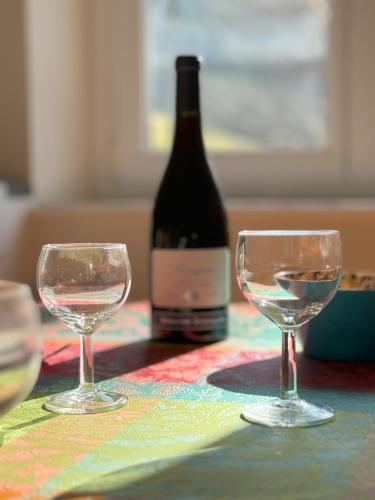 a bottle of wine and two wine glasses on a table at Chalet Cosy Lisière de Forêt in Xonrupt-Longemer