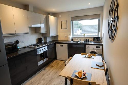 a kitchen with a wooden table and a dining room at City Retreat by the Castle Free Designated Parking in Stirling