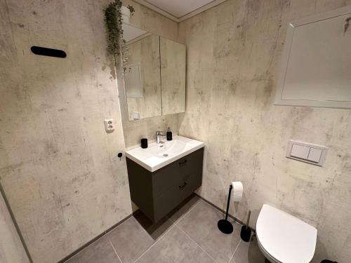 La salle de bains est pourvue d'un lavabo, d'un miroir et de toilettes. dans l'établissement Modern Central Apartment Apt 105, à Stavanger