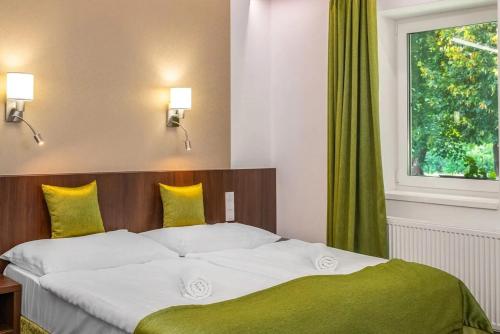 a bedroom with a large bed with a window at Szarvaskút Hotel in Zirc