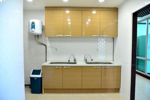 a kitchen with two sinks and a trash can at Seom Guesthouse in Seogwipo