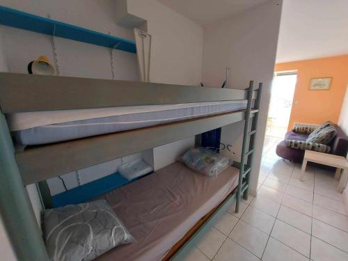 Ce lit superposé se trouve dans un dortoir doté d'un canapé. dans l'établissement Appartement lumineux 2 pièces avec terrasse, à 50m de la plage, 6 couchages, 34300 Agde - FR-1-423-177, au Grau-dʼAgde