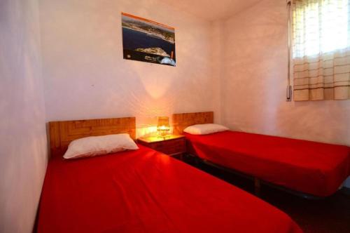 two beds in a room with red sheets at ROCAMAURA 3 - L'Estartit in L'Estartit