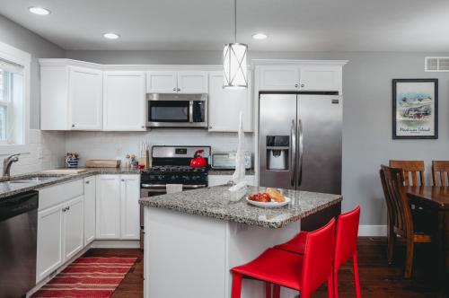 una cocina con armarios blancos y sillas rojas. en 962 Townhouse 3BR Near Downtown Beaches and Wineries, en Traverse City