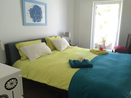a bedroom with a large bed with a yellow blanket at Odeceixe Vila in Odeceixe